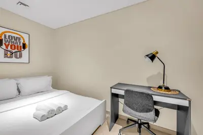 a bedroom with a desk with a bed and a chair at Waves - Comfortable JVC Apt with Balcony and Maids Room in Dubai
