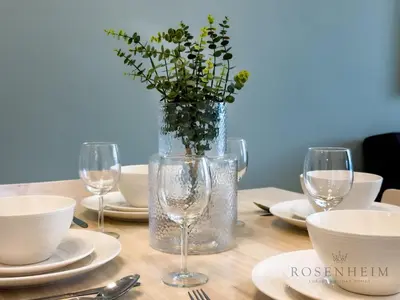 a table with glasses and a vase with flowers in it at Elevated Living at The Bay - Canal & Khalifa Views in Dubai
