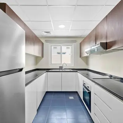 a kitchen with white cabinets and a blue tile floor at Modern 3-Bedroom Villa in Damac Hills 2 in ‘Ūd al Bayḑāʼ