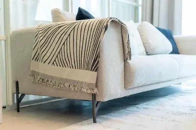 a blanket on a couch in a living room at Dubai Hills - 1BR Luxe Apartment - Golfville - by UDH in Dubai