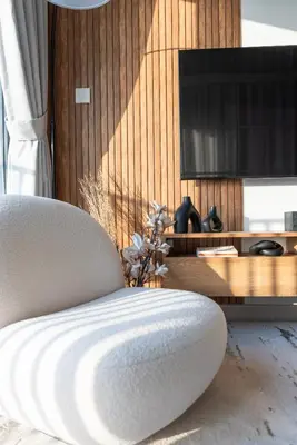a living room with a chair and a television at Dubai Hills - 1BR Luxe Apartment - Golfville - by UDH in Dubai