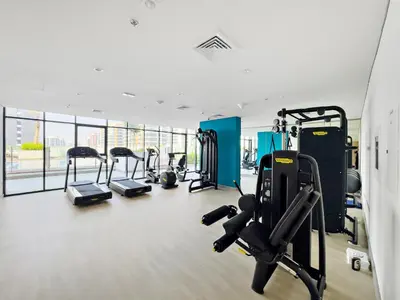 a gym with several treadmills and cardio machines at Lovely Apt Near The Burj with Pool, Gym & BBQ Area in Dubai