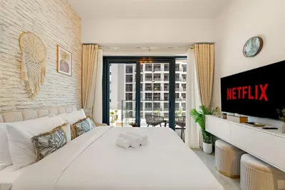 a bedroom with a white bed and a tv at Lovely Apt Near The Burj with Pool, Gym & BBQ Area in Dubai