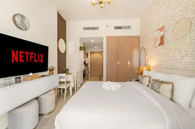 a hotel room with a white bed and a kitchen at Lovely Apt Near The Burj with Pool, Gym & BBQ Area in Dubai