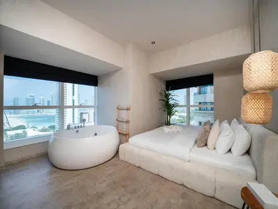 a bedroom with a large white bed and a bath tub at Upgraded Stylish Living with Private Steam Room in Dubai