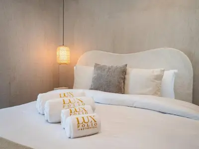 a white bed with pillows on it with a lamp at Upgraded Stylish Living with Private Steam Room in Dubai