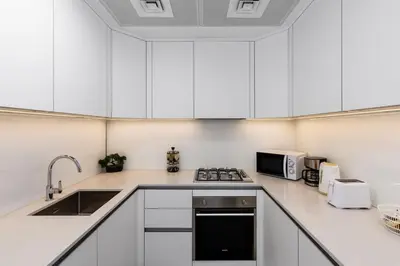 a kitchen with white cabinets and a sink and a microwave at Waves - Refined Studio with Balcony & City Views in Luma21 in Dubai