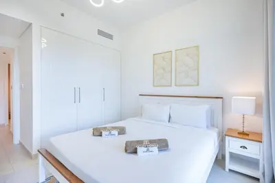 a white bedroom with a large bed with two plates on it at Beautiful Home with Full Burj View in Downtown in Dubai