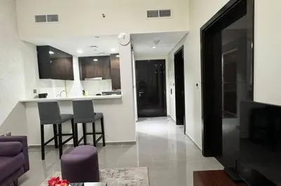 a kitchen and a living room with a couch and a tv at Home away from home in Dubai