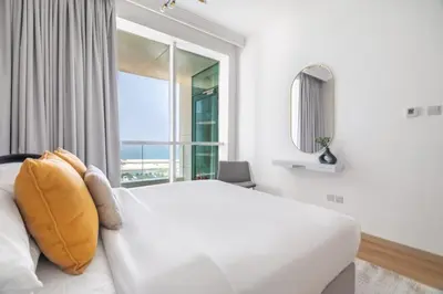 a bedroom with a white bed and a large window at GuestReady - Luxurious nest direct on JBR Beach in Dubai