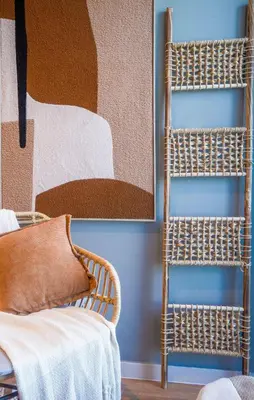 a wicker chair sitting next to a wall with a painting at Paramount Midtown I Sky High Luxury 2BR Apartment with Burj Khalifa View & Highest Infinity Pool I Down Town Dubai in Dubai