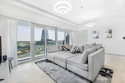 a living room with a couch and large windows at Stylish Brand New 1 Bedroom in Dubai