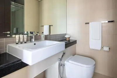 a bathroom with a white sink and a toilet at Frank Porter - Silverene Tower B in Dubai