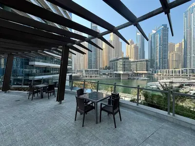 a balcony with tables and chairs and a view of a city at Frank Porter - Silverene Tower B in Dubai