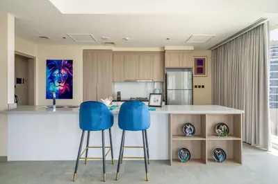 a kitchen with two blue bar stools at a counter at Deluxe Marina View 2BR - Stella Maris Retreat in Dubai