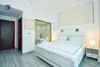 a white bedroom with a large white bed and a mirror at Luxury Escapes - Elegant 3BR Apt with 4 Balconies in 29 Blvd in Dubai