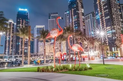 three flamingos in a park in the city at night at Palace Residence Dubai Creek Harbour 1 Bd Apt in Dubai