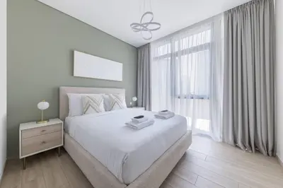 a white bedroom with a large bed and a window at Palace Residence Dubai Creek Harbour 1 Bd Apt in Dubai