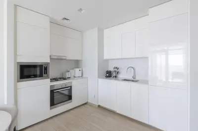 a white kitchen with white cabinets and a sink at Palace Residence Dubai Creek Harbour 1 Bd Apt in Dubai