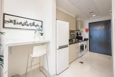 a kitchen with a white refrigerator and a white chair at Damac Hills Carson studio on Golf Course in Dubai Marina