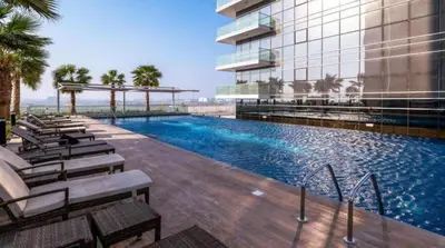 a swimming pool in front of a building at Damac Hills Carson studio on Golf Course in Dubai Marina