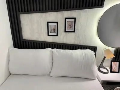 a bedroom with a bed with white pillows and a mirror at Executive Suite Room in Barsha 1 Near MOE Metro in Dubai