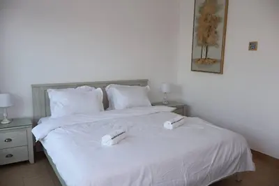 a bedroom with a white bed with two books on it at Specious 2BR VILLA WITH MAIDROOM AND HUGE GARDEN IN JVT DUBAI in Dubai