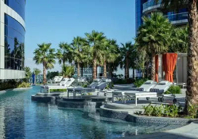 a pool with chairs and palm trees in a building at DAMAC Towers by Paramount Hotels & Resorts Dubai in Dubai