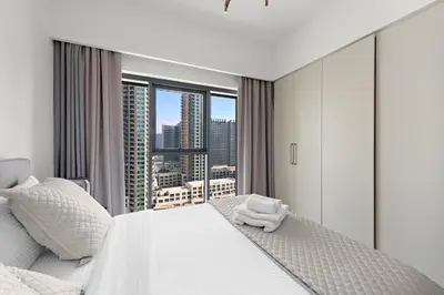 a bedroom with a white bed and a large window at Luxurious 1-Bedroom Apartment in Dubai