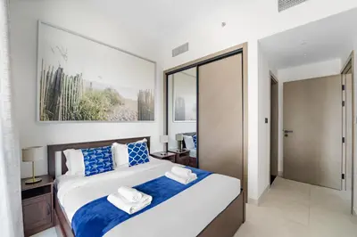 a bedroom with a large bed with blue and white pillows at Elegant 1-Bedroom Apartment in Dubai