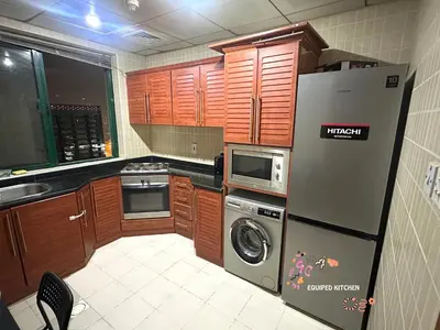 a kitchen with wooden cabinets and a refrigerator at The Hive Partition Room in Tecom Near Metro in Dubai