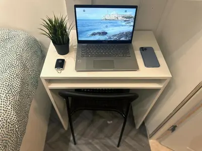 a laptop computer sitting on a desk next to a chair at Cove Partition Room in Tecom Near Internet City Metro in Dubai