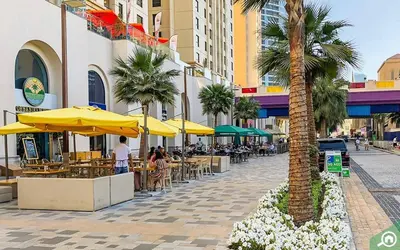 a palm tree on a street with tables and umbrellas at Luxury Studio in Murjan 2, JBR in Dubai