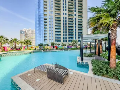 a swimming pool with two benches and a large building at Stylish 1-Bedroom in Prime Business Bay Aykon C in Dubai