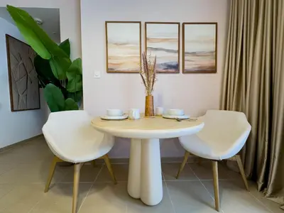 a dining room with a white table and two chairs at Naseem - Elegant Coastal Retreat with Stunning Marina Views in Dubai