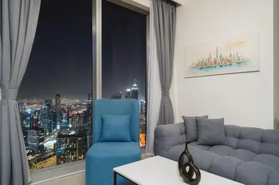 a living room with a blue couch and a window at Casa Nomad - Full Burj Khalifa & Fountain View at Luxury 4 Bed in Dubai