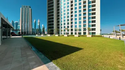 a large field of grass in front of a tall building at 4BR with Spacious Balcony & Stunning Burj Khalifa Views in Dubai