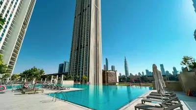 a swimming pool with lounge chairs and a city skyline at 4BR with Spacious Balcony & Stunning Burj Khalifa Views in Dubai