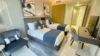 a hotel room with two beds and a desk at Appartement spacieux de luxe à 5mn du Burj Khalifa in Dubai