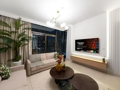 a living room with a couch and a tv on a wall at 2BR-Downtown Apartment- 10 Min Walk to Dubai Mall in Dubai