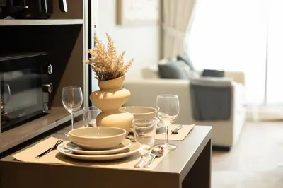 a table with plates and wine glasses and a vase at WelHome - LOCI Residences in Dubai
