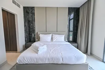 a bedroom with a large bed with white sheets at Chic Retreat 1BR in District One Meydan in Dubai