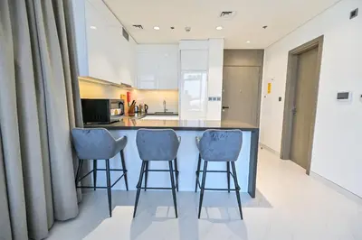 a kitchen with a island with three bar stools at Chic Retreat 1BR in District One Meydan in Dubai