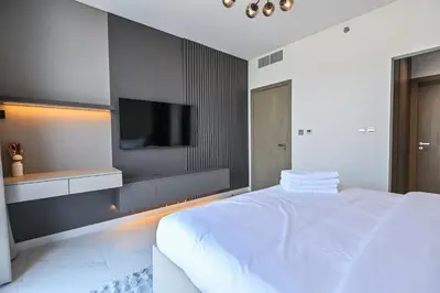 a bedroom with a white bed and a flat screen tv at Chic Retreat 1BR in District One Meydan in Dubai