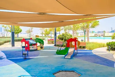 a playground in a park with an orange canopy at Paradise1BR by the Crystal Lagoon in District One Meydan in Dubai