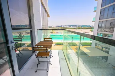 a balcony with chairs and a swimming pool in a building at Gorgeous 1 Bedroom in District One Meydan in Dubai