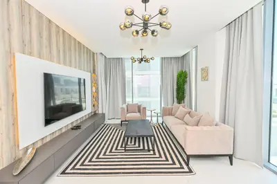a living room with a tv and a couch and chairs at Gorgeous 1 Bedroom in District One Meydan in Dubai