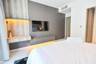 a bedroom with a white bed and a flat screen tv at Gorgeous 1 Bedroom in District One Meydan in Dubai