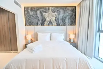 a bedroom with a large white bed with two lamps at Gorgeous 1 Bedroom in District One Meydan in Dubai