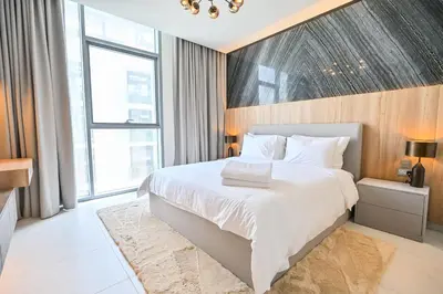 a bedroom with a white bed and a large window at Luxury and Spacious 1 Bedroom in District One Meydan in Dubai